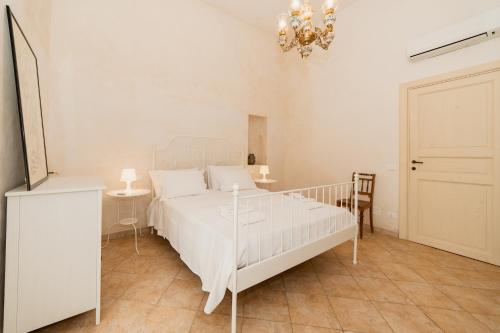a bedroom with a white bed and a chandelier at CASA PAPADIA in Uggiano la Chiesa