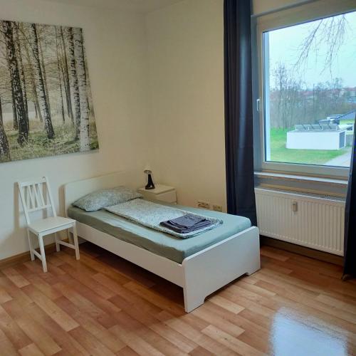 a bedroom with a bed and a chair and a window at Leuna - Kurzzeitvermietungen direkt bei den Leunawerken, 2-3 Schlafzimmer in Leuna