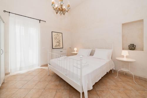 a white bedroom with a white bed and a chandelier at CASA PAPADIA in Uggiano la Chiesa