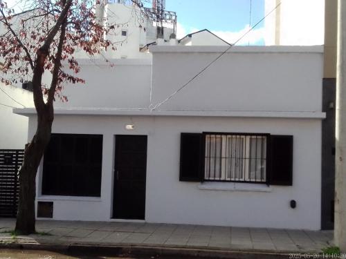 a white house with black windows and a tree at house city in Mar del Plata
