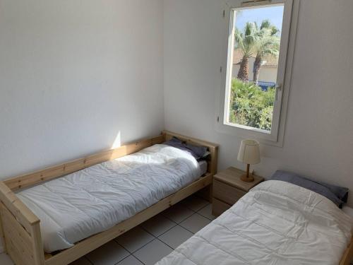 deux lits dans une chambre avec une fenêtre dans l'établissement Résidence sécurisée avec piscine, T2 duplex, parking privé, climatisation, à La Seyne-sur-Mer