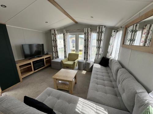 a living room with a couch and a tv at Dainville Caravan Park in Skegness