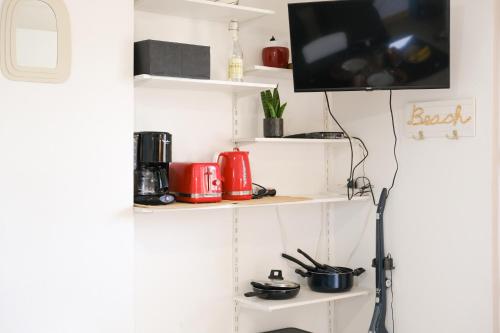 une cuisine avec des étagères blanches et une télévision sur un mur dans l'établissement Le petit Val, à Criel-sur-Mer