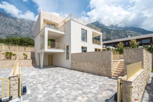 a white house with mountains in the background at NEW! Villa Adore Makarska in Makarska