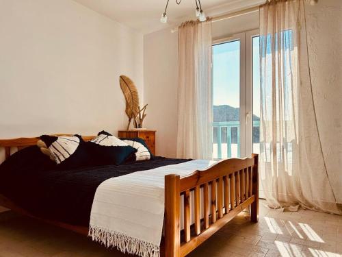 une chambre avec un grand lit et une grande fenêtre dans l'établissement Villa Casapalmea on Mute Beach, Cap Corse, à Centuri