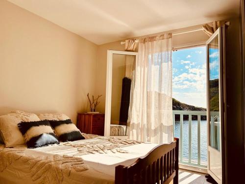 a bedroom with a bed and a large window at Villa Casapalmea on Mute Beach, Cap Corse in Centuri