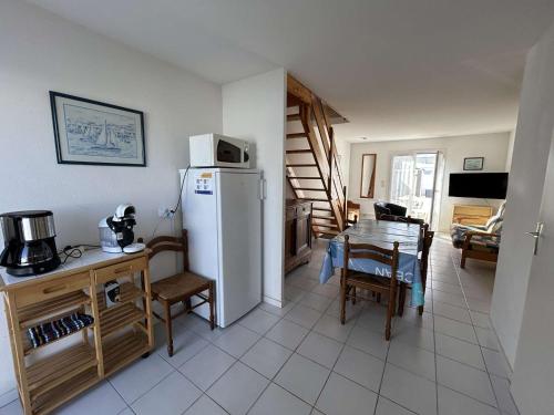 Il comprend une cuisine équipée d'un réfrigérateur et d'une table avec des chaises. dans l'établissement Maison 3 pièces près de la plage - 2 chambres, jardin privé, parking et ménage inclus - FR-1-224C-223, à Saint-Hilaire-de-Riez