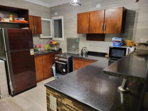 eine Küche mit Holzschränken und einer schwarzen Arbeitsplatte in der Unterkunft Town house Raselhakma north coast egypt in Ras Elhekma