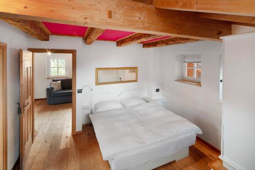 カンピテッロ・ディ・ファッサにあるDolomites Chalet Pianの白いベッドと木製の天井が備わるベッドルーム1室が備わります。