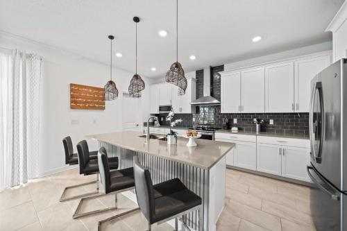 a kitchen with white cabinets and a large island with chairs at 390 Strand Drive in Melbourne Beach