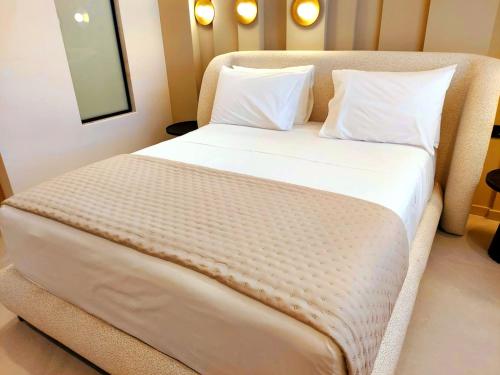 a bed with white sheets and pillows in a room at Minares Luxury Suite in Rethymno Town