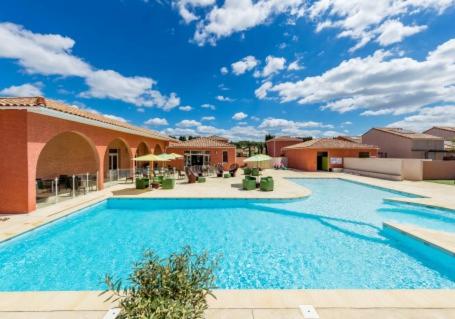 une grande piscine devant un immeuble dans l'établissement Natacha & Bacchus, à Saint-Christol