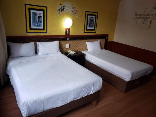 two beds in a hotel room with a phone between them at Hotel Benedicta in Mexico City