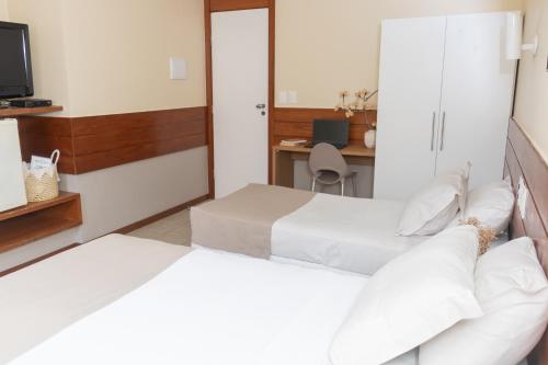 two beds in a room with a desk at Portal Da Praia Hotel in Fortaleza