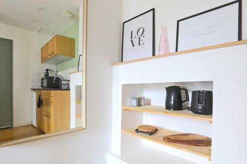une cuisine avec des étagères en bois et un miroir dans l'établissement Le Olry - Studio 2 personnes - Terrasse - Cosy, à Nancy