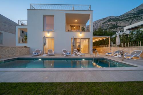 a villa with a swimming pool in front of a house at NEW! Villa Adore Makarska in Makarska