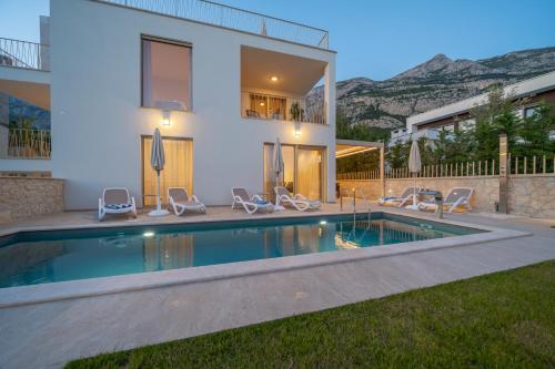 a house with a swimming pool in front of a house at NEW! Villa Adore Makarska in Makarska
