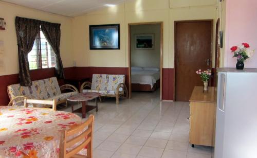 a living room with a table and a kitchen with a refrigerator at Mile 36 Lodge in Kundasang