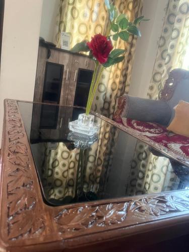 a mirror on top of a table with a rose at Al Mubeen home stay in Nishāt