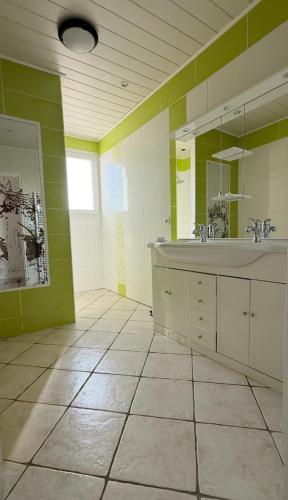 une salle de bain avec un grand lavabo et un miroir dans l'établissement L'échappée, à Bouin