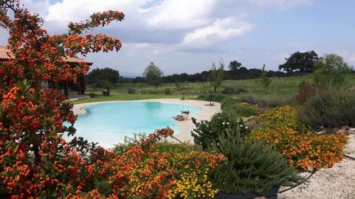 a swimming pool in a garden with flowers at Tenuta Soria Location immersa nel verde con piscina privata in Frassino