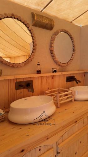 a bathroom with two sinks and two mirrors on a counter at Dihya desert camp in Merzouga