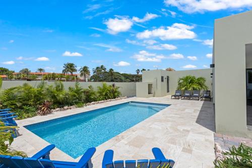 a swimming pool with blue chairs and a swimming pool at Villa Jasmijn met privezwembad, Mambo Beach in Willemstad