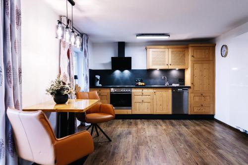 kuchnia z drewnianymi szafkami, stołem i krzesłami w obiekcie Haus Johannishof w mieście Mittenwald