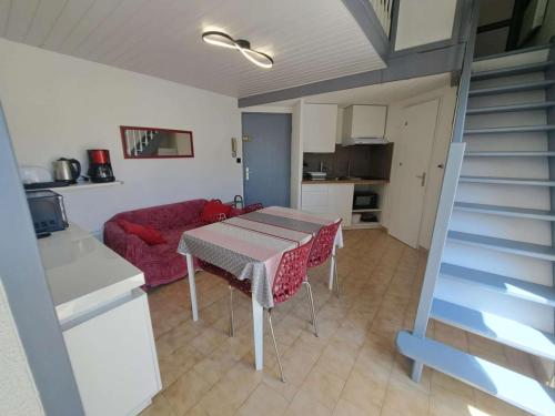 un salon avec une table et un canapé rouge dans l'établissement Appart 2 pièces mezzanine clim, bord de plage, parking - FR-1-326-722, à Marseillan