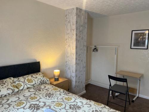 ein Schlafzimmer mit einem Bett, einem Stuhl und einem Schreibtisch in der Unterkunft Five Oaks House- Entire 3 Bedroom House for Family & Contractors with up to 5 sleep- NO PARTIES ALLOWED in Willenhall