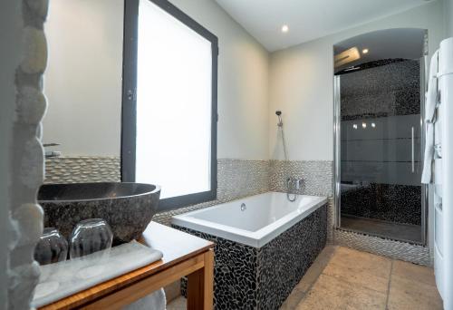 a bathroom with a large tub and a sink at La Belle Vie in Saint-Hilaire-dʼOzilhan