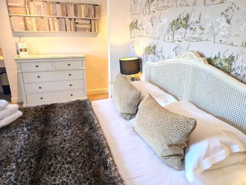a bedroom with a white bed with pillows and a dresser at Mill End Hotel in Chagford