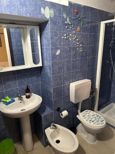 a blue tiled bathroom with a toilet and a sink at Affittacamere l'Acciuga in La Spezia