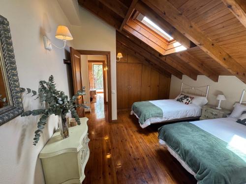 a bedroom with two beds in a room with wooden ceilings at Casa de Robles Cantabria, en el corazón de los Valles Pasiegos in Sel de la Carrera