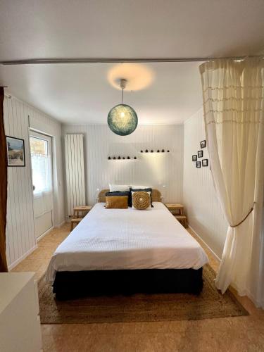 - une chambre avec un grand lit et une lampe pendant dans l'établissement Appartement rdc proche plage, commerces et gare, à Pornichet