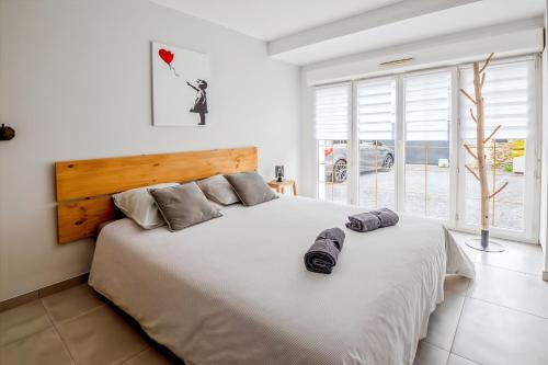 - une chambre dotée d'un grand lit blanc avec deux chaussures dans l'établissement Maison Cosy Campagne, Terrasse & Spa, à Le Plessis-Feu-Aussoux