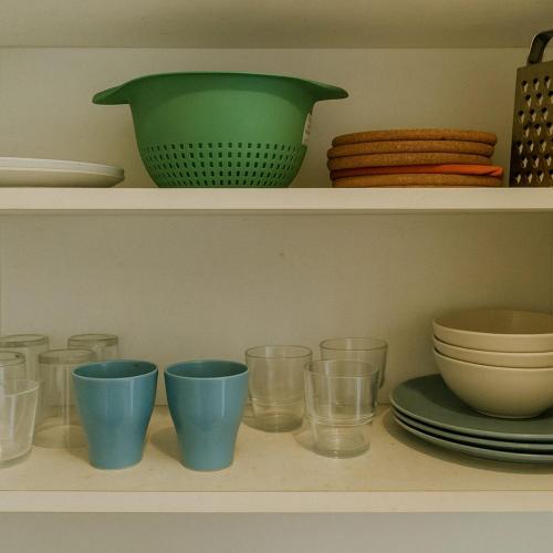 une étagère avec des tasses, des assiettes et des bols dans l'établissement Fontanières Charming studio on the edge of Lyon, à La Mulatière