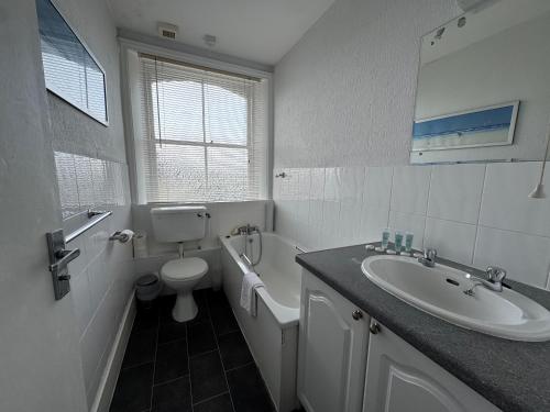 Un baño blanco con lavabo e inodoro. en Devonshire House Holiday Flats, en Eastbourne
