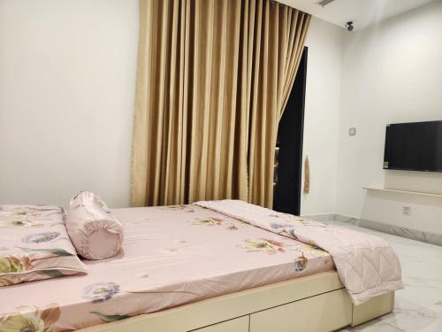 a bedroom with a bed with pink sheets and a television at The Beverly-BE2-Vinhomes Grand Park in Gò Công