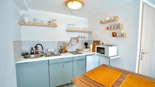 a kitchen with blue cabinets and a sink and a microwave at La Parenthèse Impressionniste in Limetz