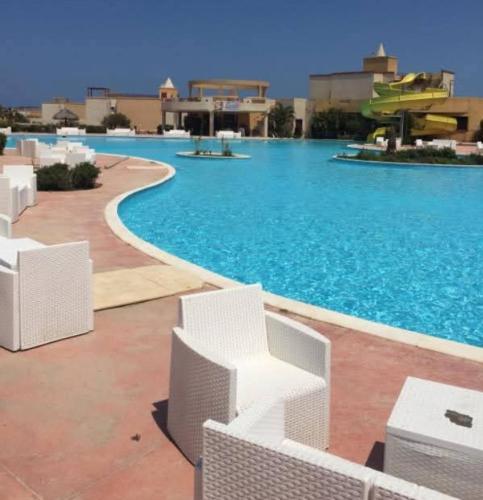a swimming pool with white chairs in a resort at شاليه ديمورا عائلات فقط Dimora Chalet Only Family in Dawwār Muḩammad Abū Shunaynah