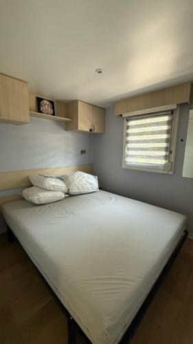 un grand lit blanc dans une chambre avec une fenêtre dans l'établissement L aube, à La Bernerie-en-Retz