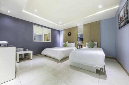 two beds in a bedroom with blue walls at Sangmu Nemo Hotel in Gwangju