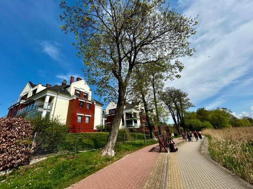 a tree on a brick sidewalk in front of a house at Lakeside Promenade View Studios in Ostróda