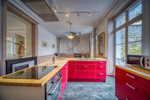 une cuisine avec des armoires rouges et un comptoir dans l'établissement R'Apparts T4 Le Prieuré, à Grenoble