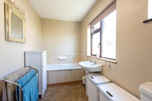 ein Bad mit einem Waschbecken, einer Badewanne und einem Fenster in der Unterkunft The Cottage - Holiday home in Reedham on the Southern Norfolk Broads in Reedham