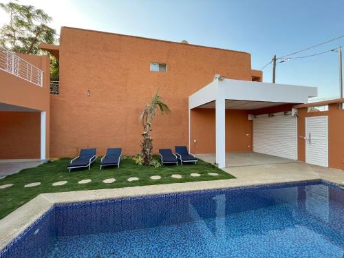 a house with a swimming pool and two blue chairs at Villa John et Nini in Saly Portudal
