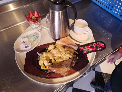 a table with a plate of food and a coffee pot at Albany Merchants Hotel in Albany