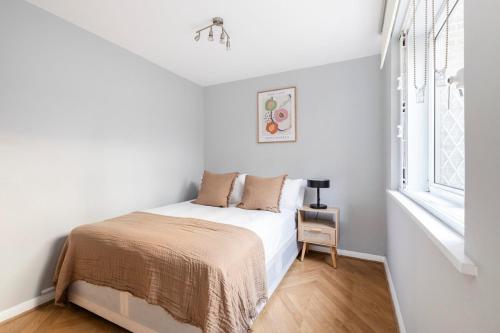 a white bedroom with a bed and a window at Excellent 3 bed House Hyde Park in London