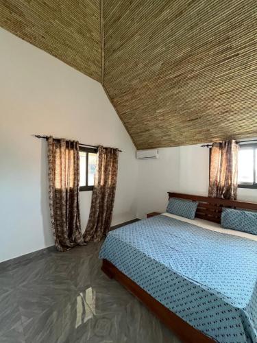 a bedroom with a bed and two windows at Villa John et Nini in Saly Portudal